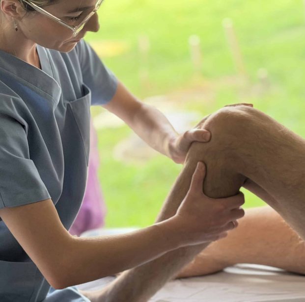 Anna Monlezun, ostéopathe à Montgiscard, manipulant le genou d'un patient pour soulager des douleurs musculaires et articulaires, dans son cabinet lumineux.