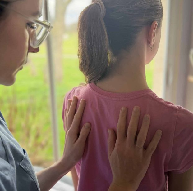 Anna Monlezun, ostéopathe à Montgiscard, effectue une palpation du dos d'une jeune patiente pour un suivi postural en ostéopathie pédiatrique.